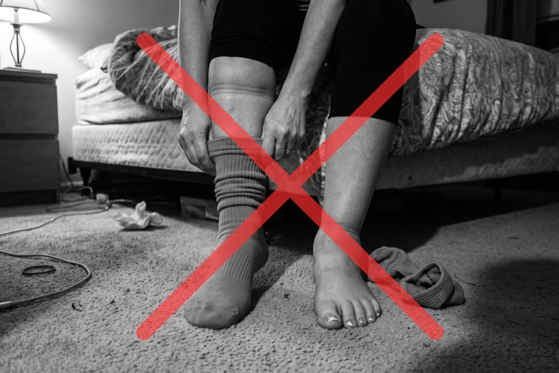 Woman pulling on compression socks, crossed out in red — compression only moves fluid temporarily